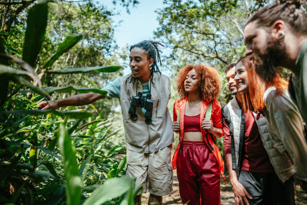 Tourist guide showing plants to a group of friends in the forest